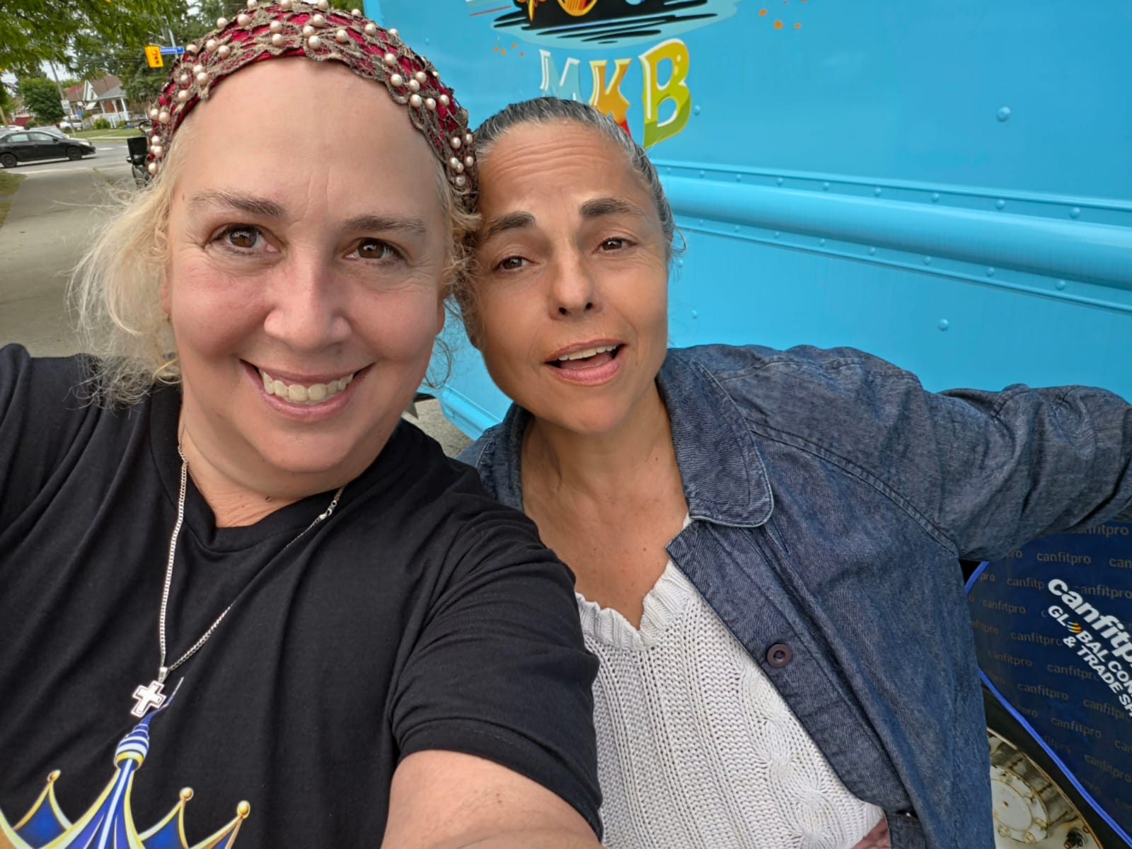 Two community volunteers at an outreach event beside a food truck
